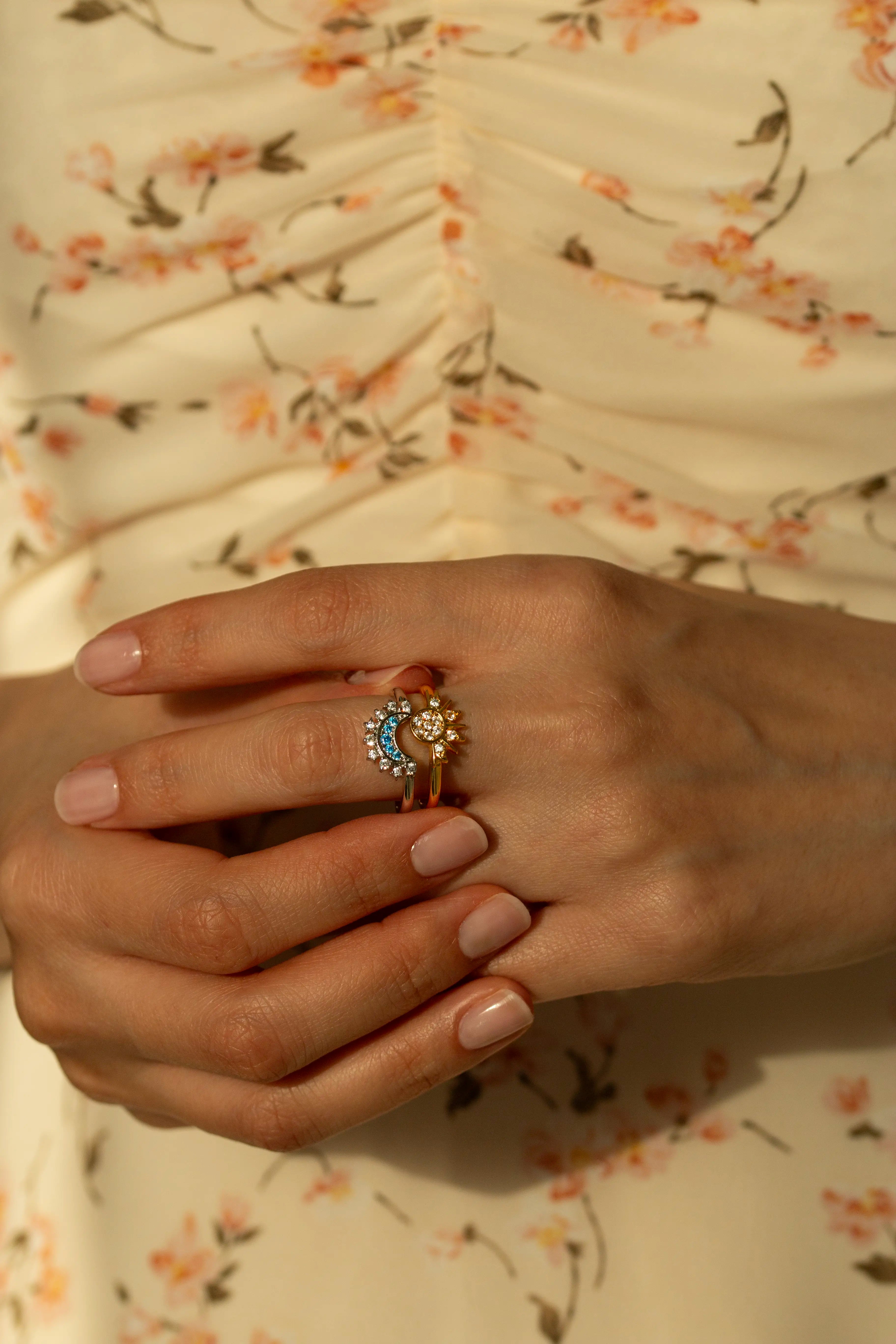 Trendy celestial sun and moon matching rings featuring blue topaz colored stones and pavé cz crystals. Aesthetic bohemian mixed metal stacking ring set styled with delicate white flowers.