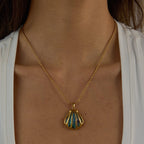 Gold necklace with a shell pendant worn by a person