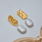 Gold and pearl earrings on a light gray background
