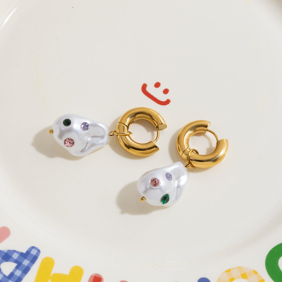 Pair of gold hoop earrings with pearl-like ends on a colorful background