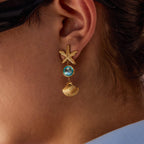 Gold earring with starfish and shell design worn by a person