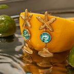 Gold earrings with starfish and turquoise stones on a yellow background