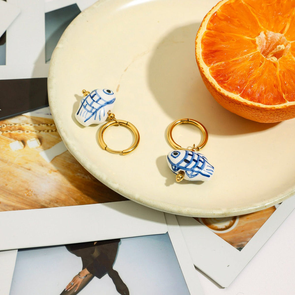 Pair of earrings with fish design on a plate with an orange