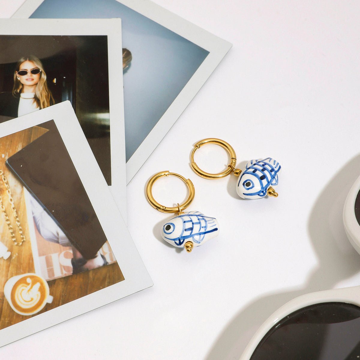 Two keychains with fish designs on a white surface with photos and sunglasses.