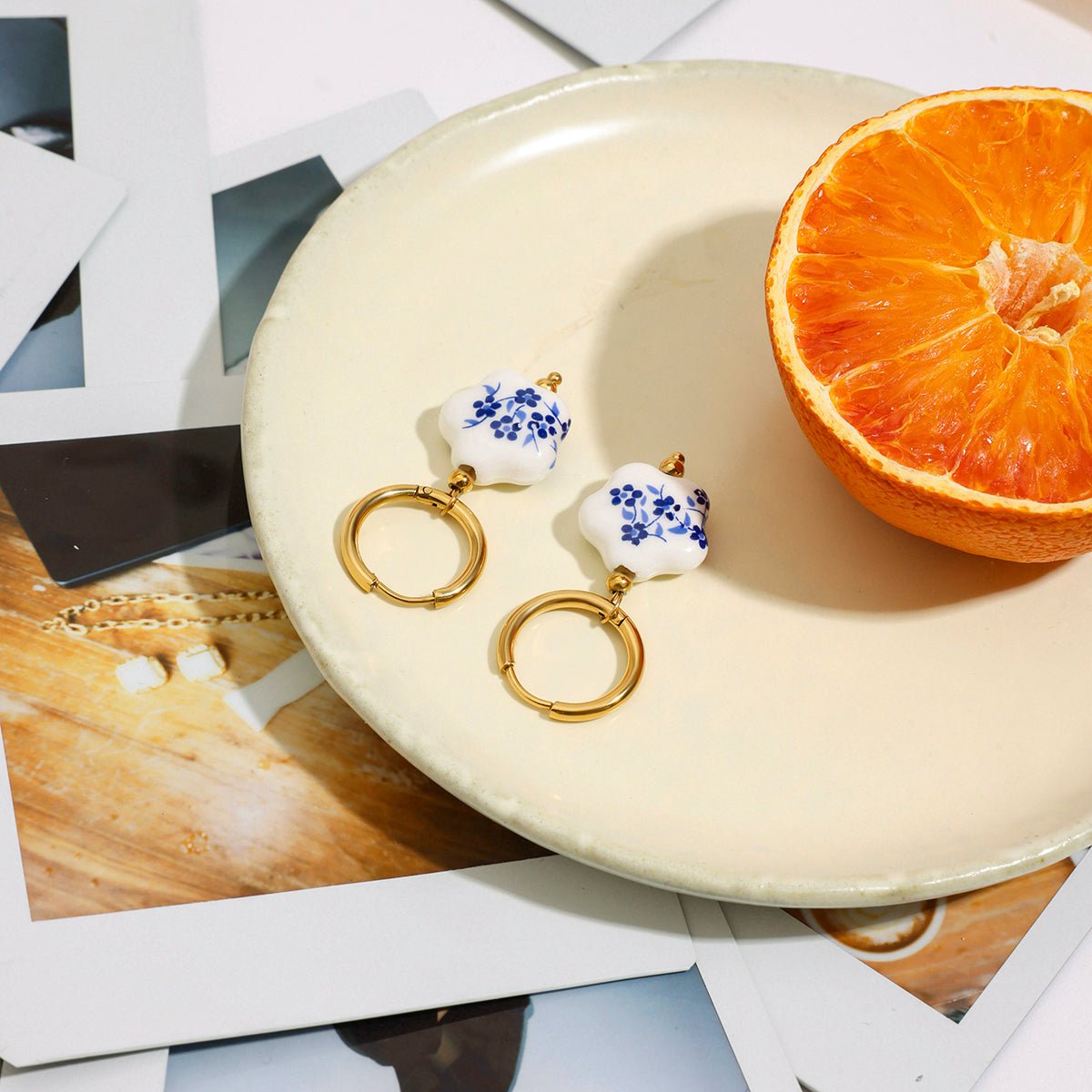 Jewelry set with floral earrings on a white plate next to an orange