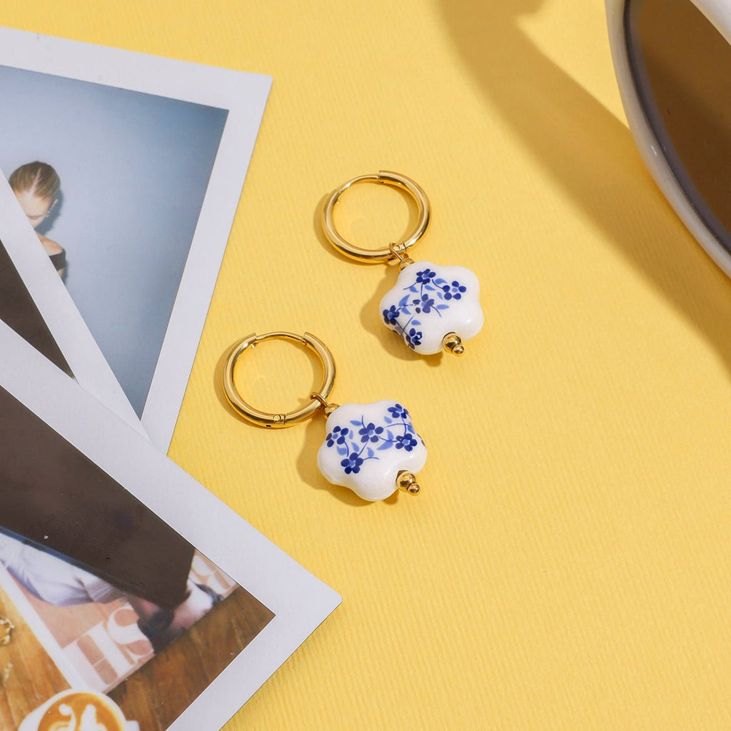 Heart-shaped keychains with floral design on a yellow surface with photos and a cup.
