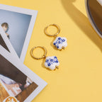 Heart-shaped keychains with floral design on a yellow surface with photos and a cup.