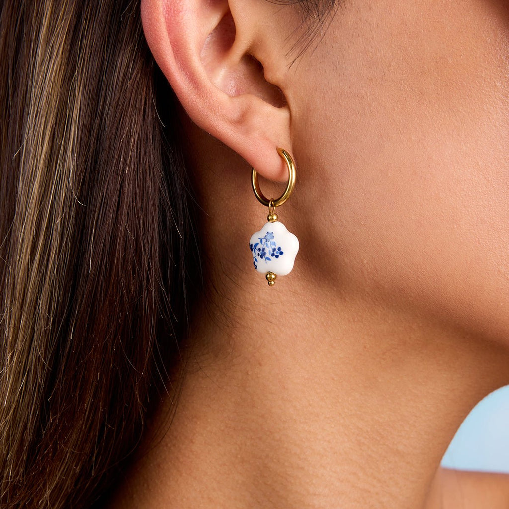 Close-up of an earring with a floral design on a person's ear.