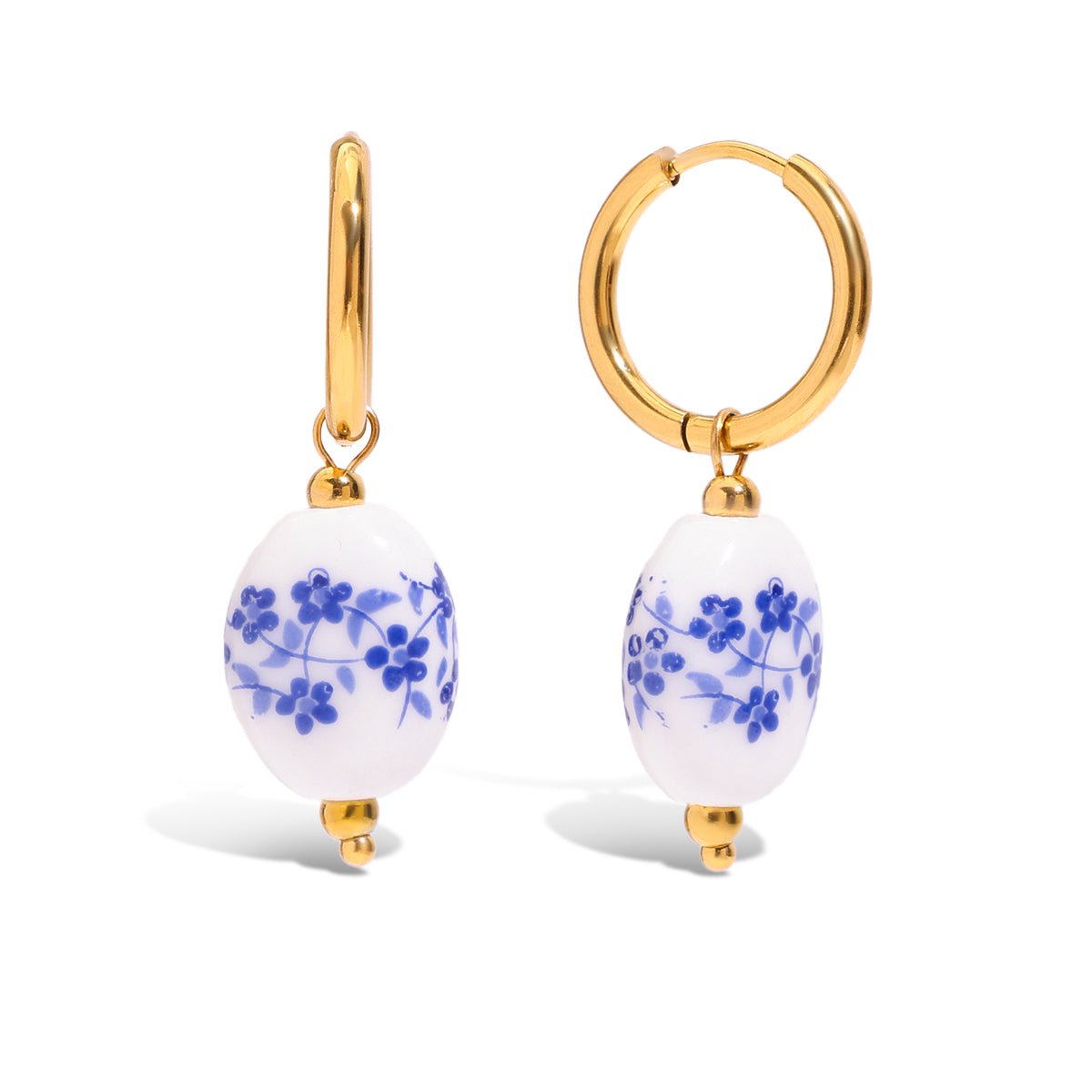 Gold hoop earrings with white beads featuring blue floral patterns on a white background