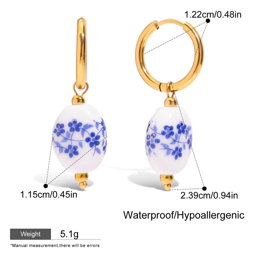 Gold hoop earrings with white beads featuring blue floral patterns, showing measurements and product details.