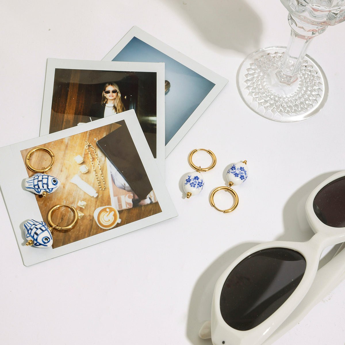 Jewelry set with earrings and rings displayed on a white surface with photos and sunglasses.