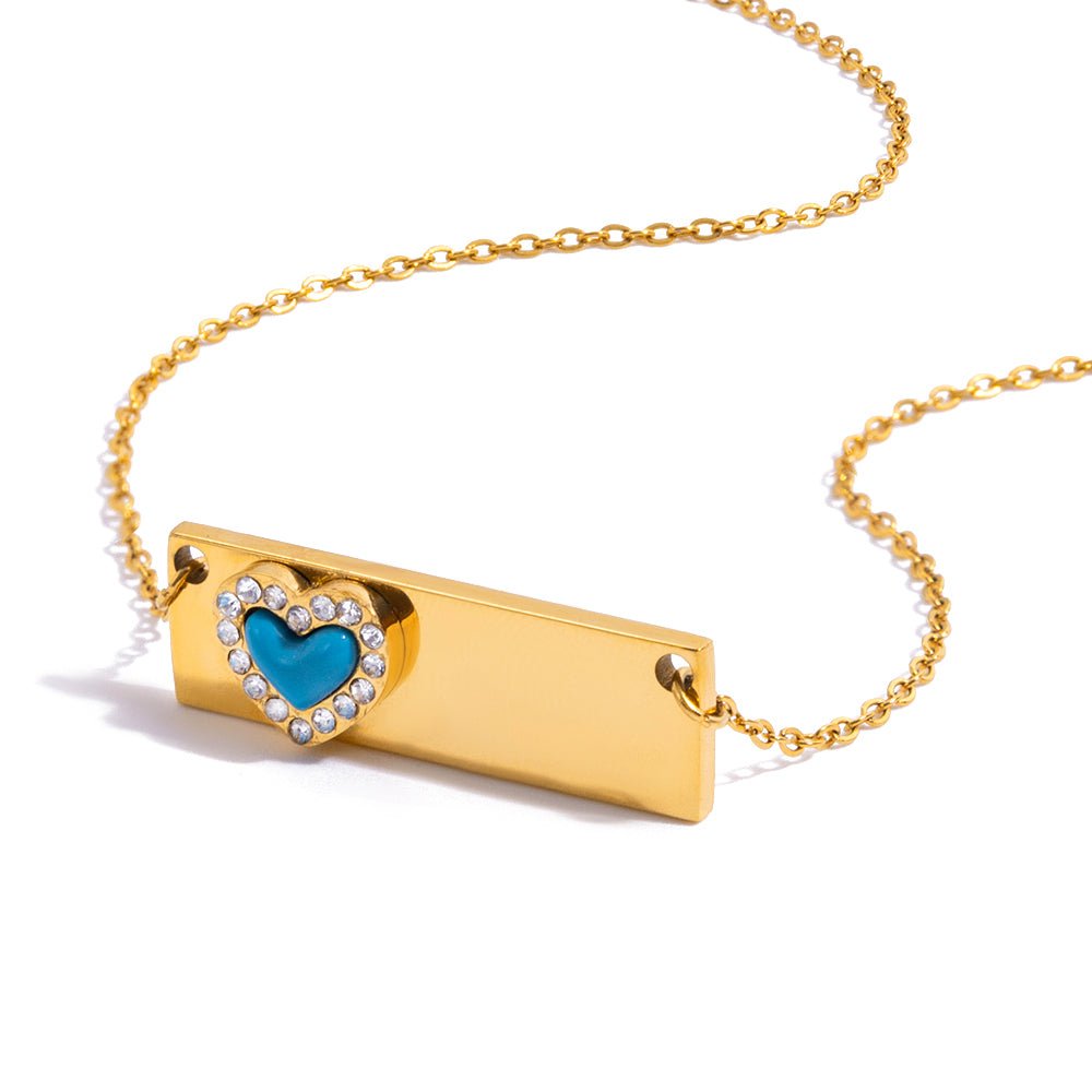 Gold necklace with a heart-shaped pendant featuring a blue gemstone on a white background