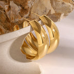Gold hoop earrings on a textured surface with a stone background