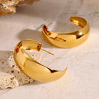 Gold hoop earrings on a textured beige surface