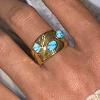 Gold ring with turquoise stones on a finger