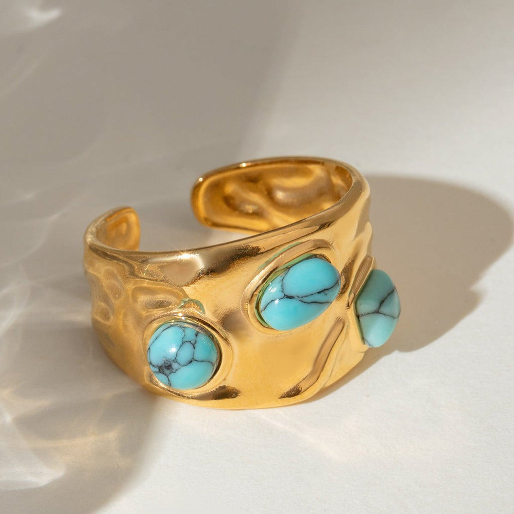 Gold ring with turquoise stones on a light background