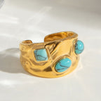 Gold ring with turquoise stones on a white background