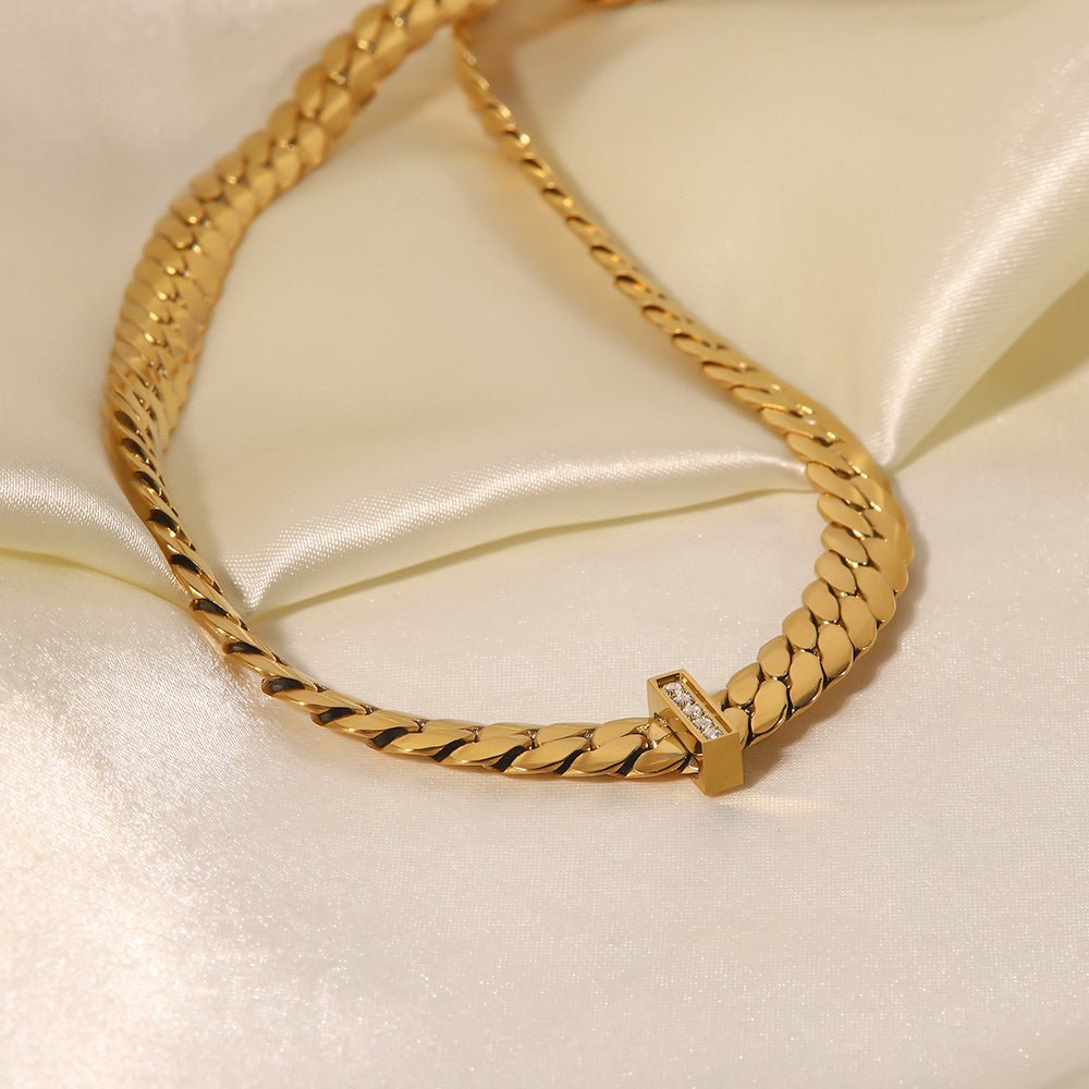 Gold chain bracelet with a diamond clasp on a light beige satin background