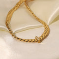 Gold chain bracelet with a diamond clasp on a light beige satin background