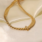 Gold chain bracelet with a diamond clasp on a light beige satin background
