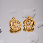 Pair of gold spiral earrings on a textured white surface