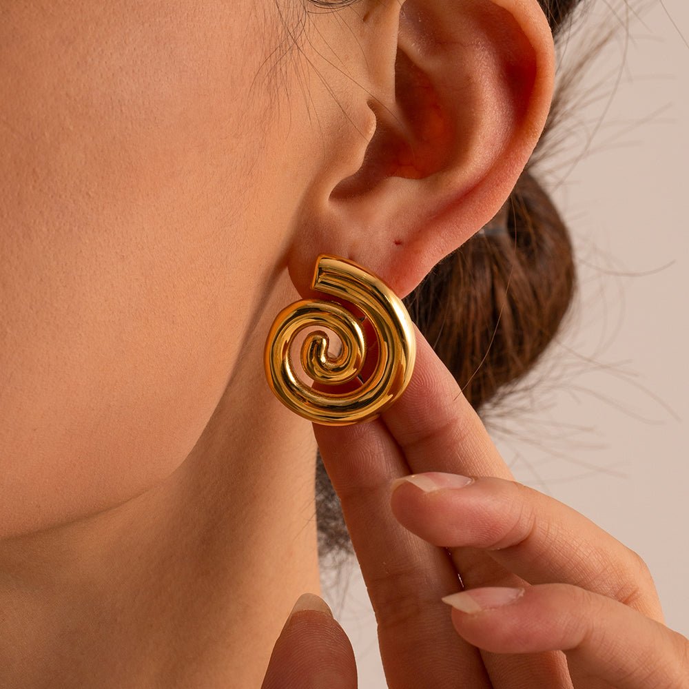 Gold spiral earring being worn on an ear with a neutral background