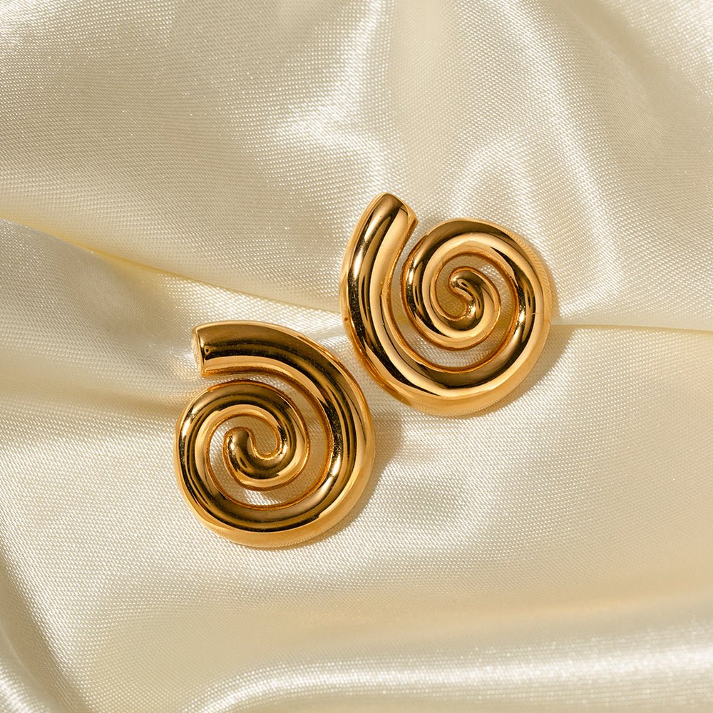 Gold spiral earrings on a satin surface