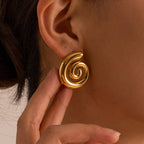 Gold spiral earring worn by a person with a neutral background