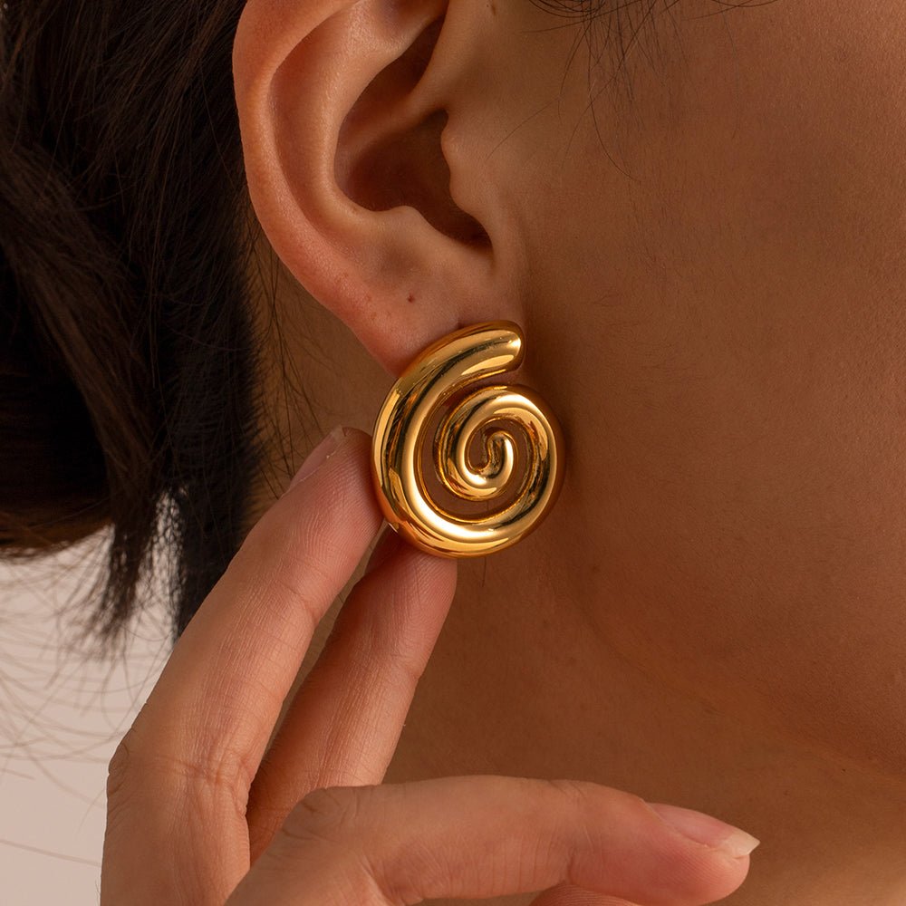 Gold spiral earring worn by a person with a neutral background