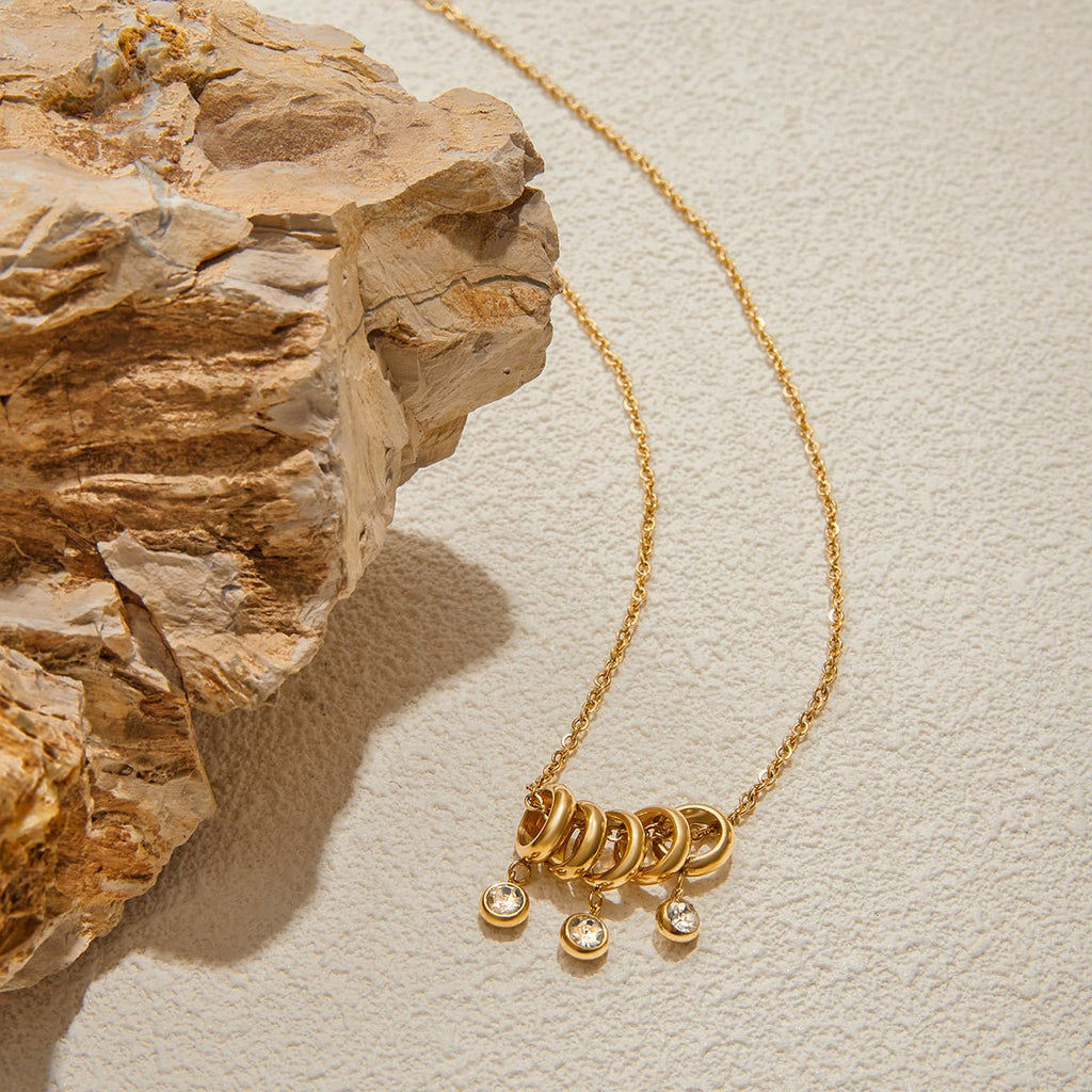 Gold necklace with pendant on a textured beige surface