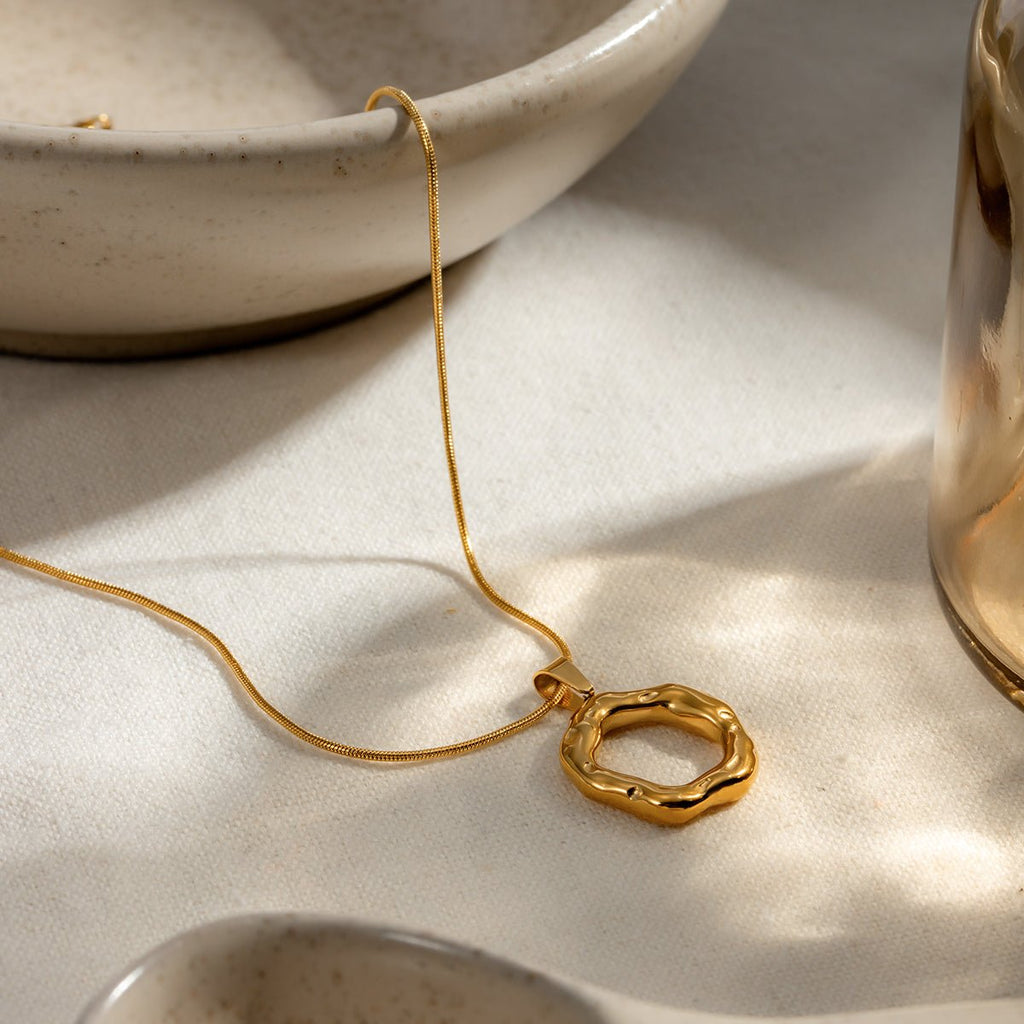 Gold necklace with a unique pendant on a light surface