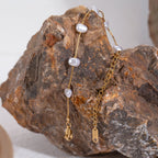 Gold chain earrings with pearls on a textured rock surface