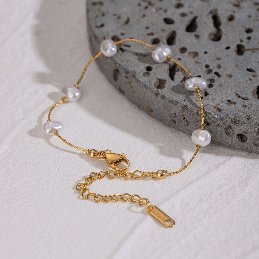 Gold bracelet with pearls on a textured stone surface