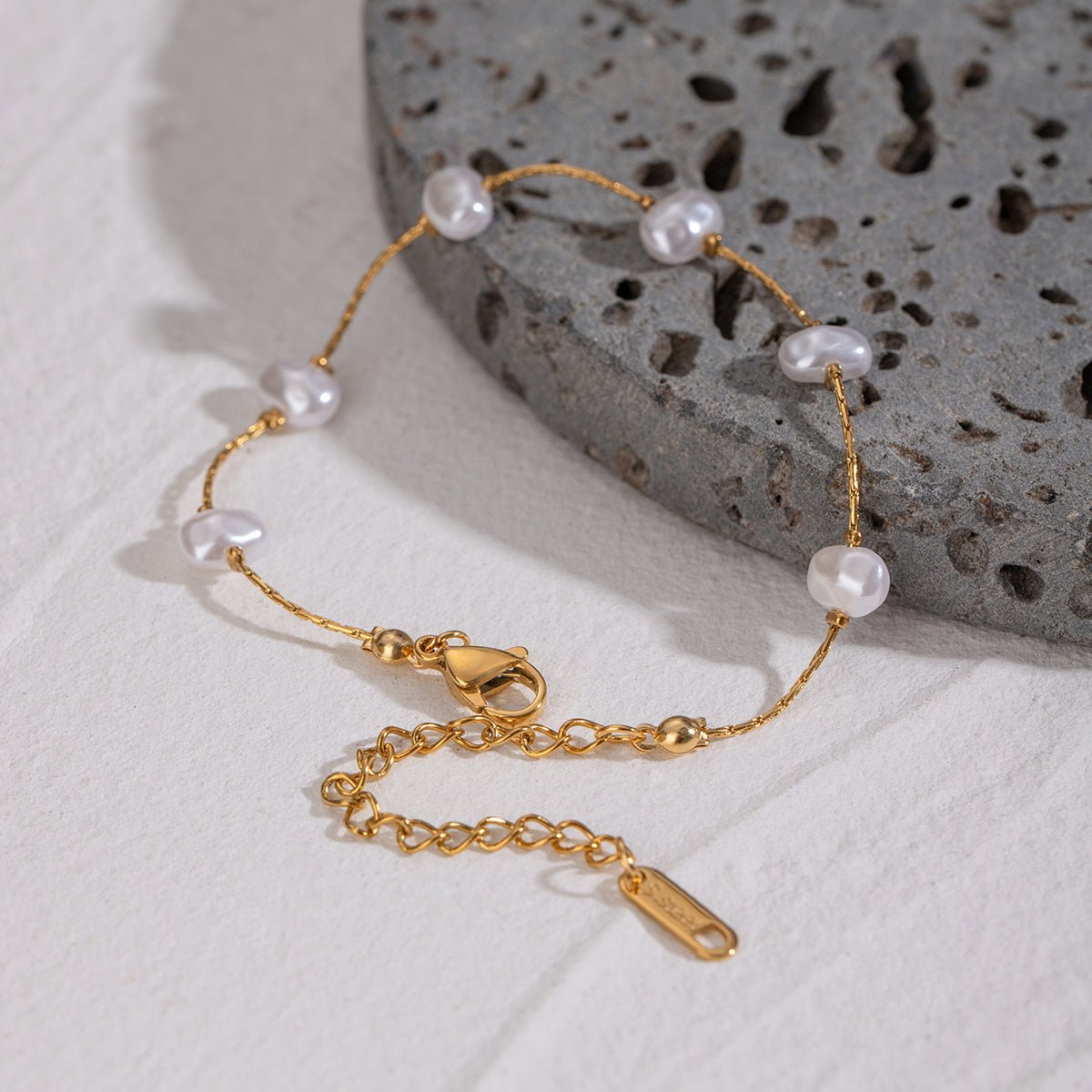 Gold bracelet with pearls on a textured stone surface