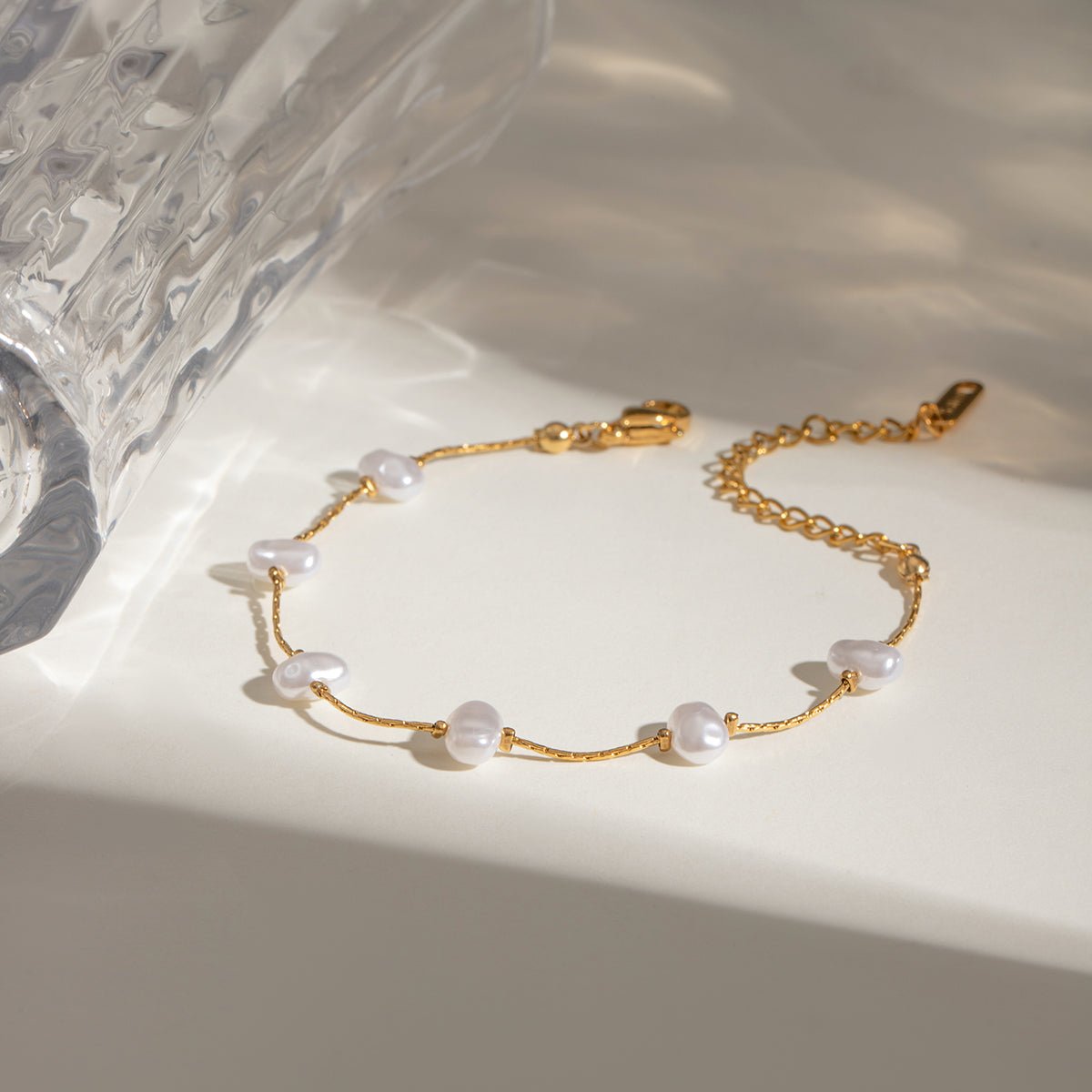 Gold bracelet with pearls on a marble surface