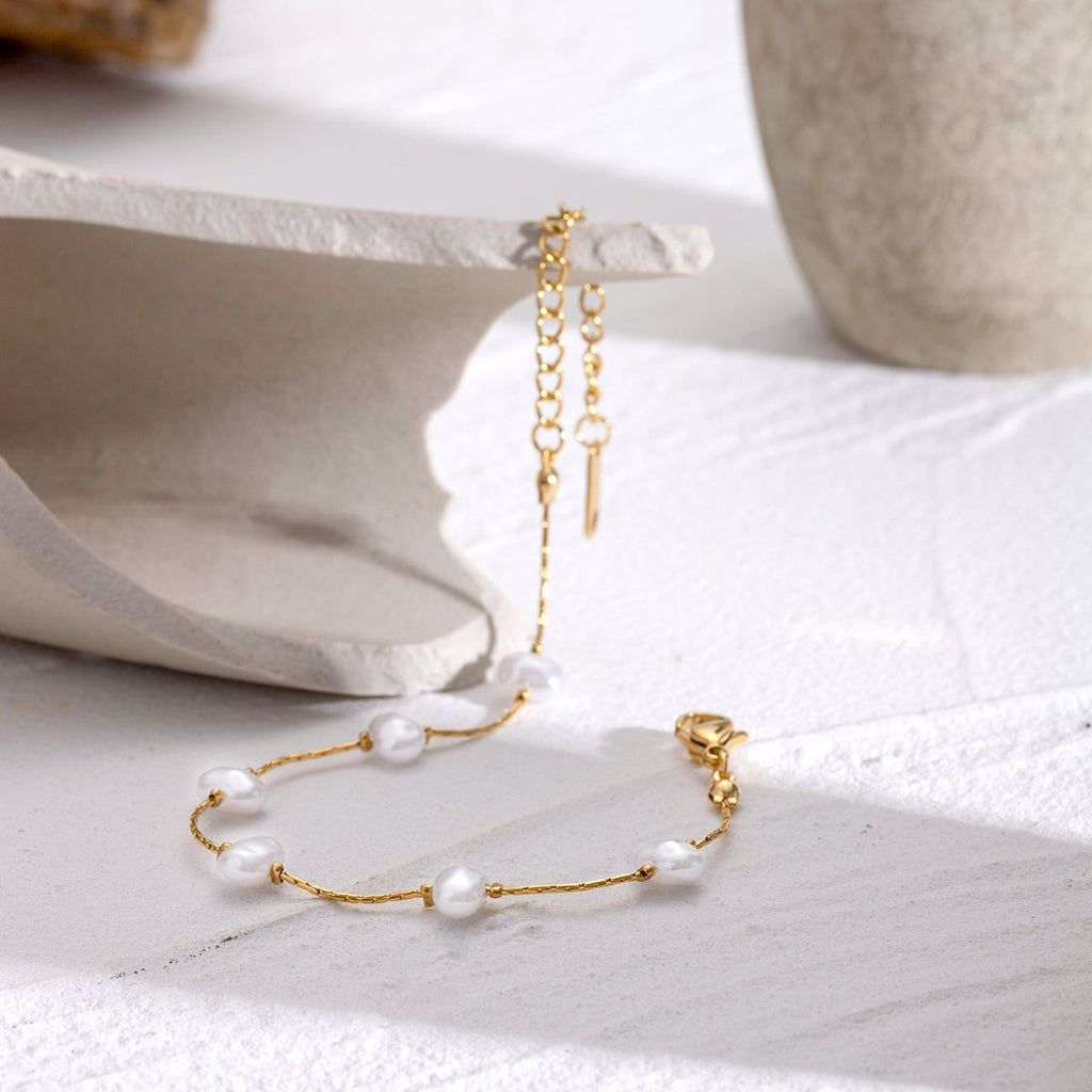 Gold bracelet with pearls on a white surface