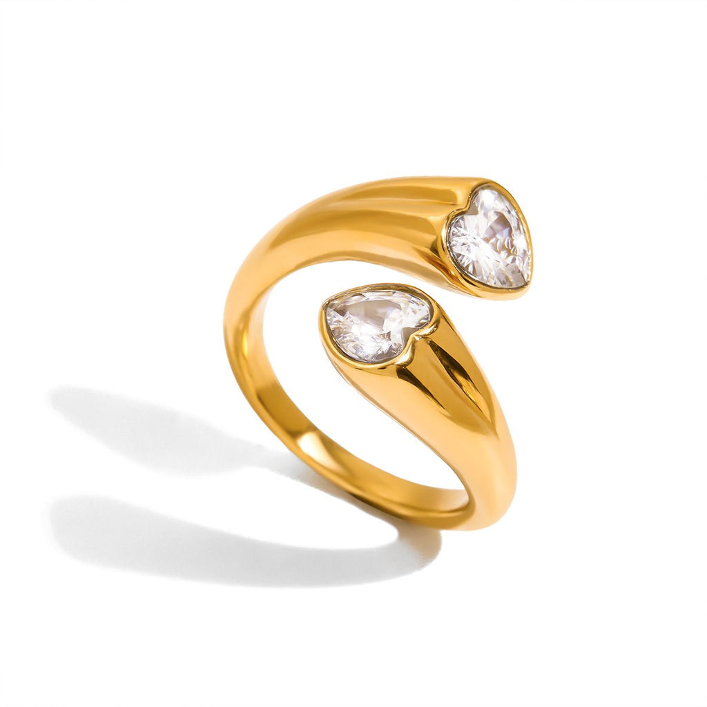 Gold ring with two heart-shaped gemstones on a white background