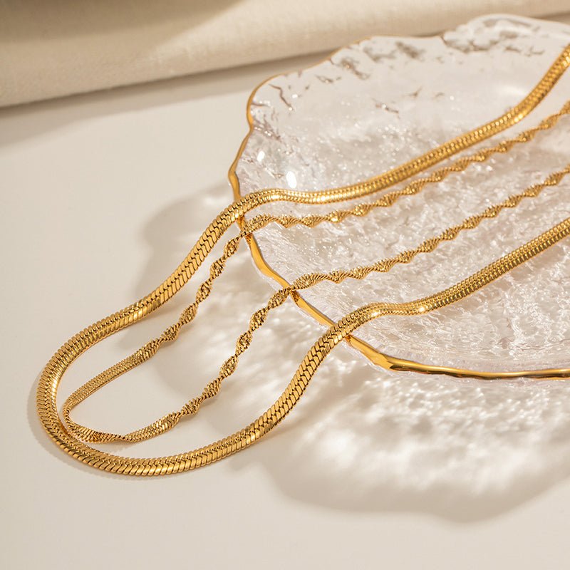 Two gold necklaces on a textured white surface