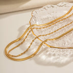 Two gold necklaces on a textured white surface