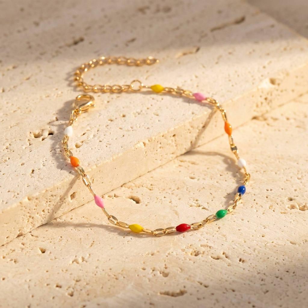 Malibu multi-color enamel lip chain bracelet in 18k gold PVD plated stainless steel on a beige stone surface.