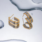 Gold and silver hoop earrings on a reflective water surface