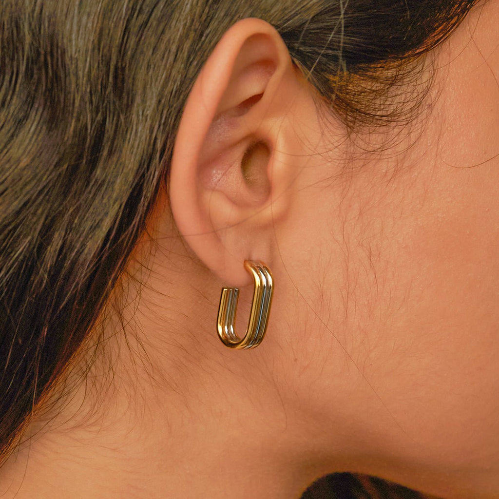 Gold hoop earring worn by a person with dark hair.
