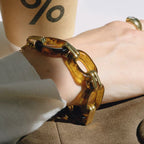 Close-up of a hand wearing a gold chain bracelet with a blurred background