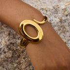 Gold bracelet on a wrist against a textured surface