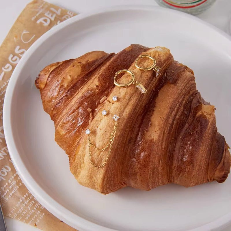 Croissant with gold jewelry on a white plate