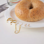 Gold earrings on a white plate with a bagel in the background
