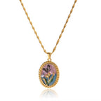 Gold necklace with a pendant featuring a floral design on a white background