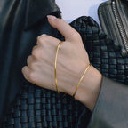 Hand wearing a gold bracelet with a textured black background