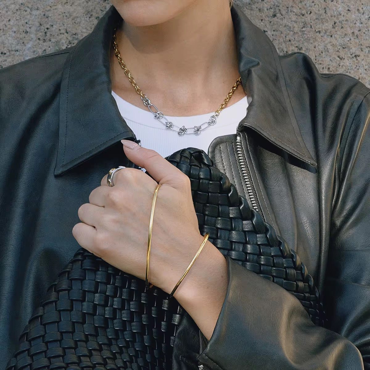 Person wearing a green leather jacket, white shirt, and gold jewelry.