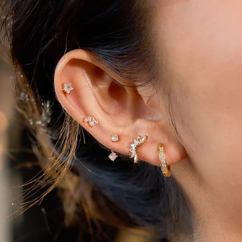 Close-up of an ear with multiple diamond earrings against a blurred background